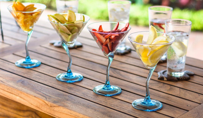 Image of three drinking glasses with freshly colored food in each sitting on a table with a glass of water in the background/  No links in this image